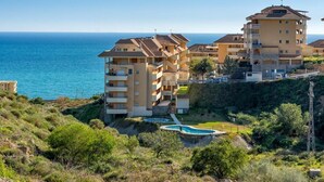 Zona residencial costera con edificios de varios pisos, piscina y vista al mar.