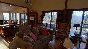 Un salon spacieux avec un grand canapé, un coin repas et une cuisine visible à travers une porte ouverte.