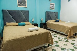 Dos camas individuales con cabeceras, mesitas de noche pequeñas con lámparas y una toalla doblada cuidadosamente sobre cada cama.
