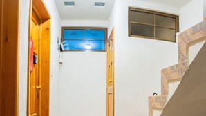 A narrow hallway with a tiled floor, a wooden door on the left, and a staircase on the right. - Atitlans House  (Panajachel)