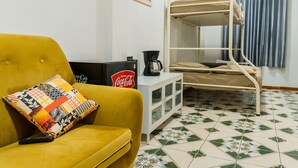 A room with a yellow sofa, a bunk bed, a small cabinet, and a Coca-Cola sign. - Atitlans House  (Panajachel)