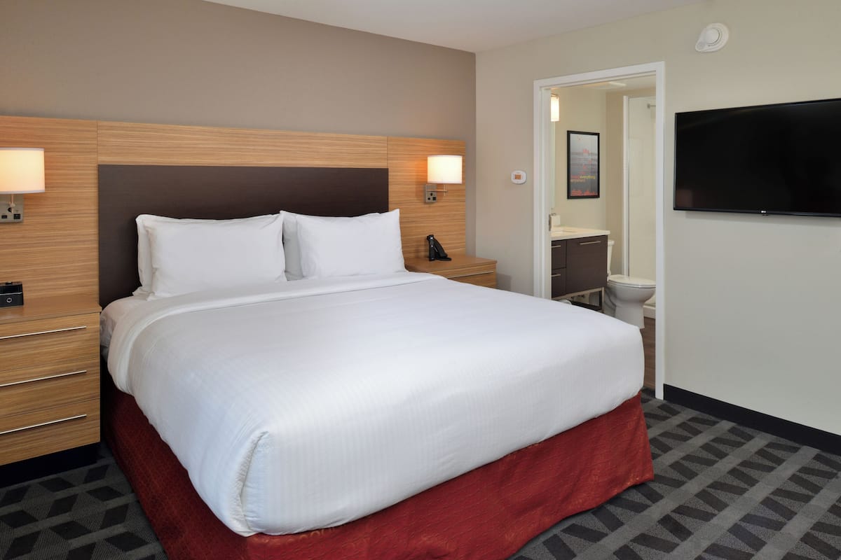 Une chambre d’hôtel avec un grand lit, des lampes de chevet, un téléviseur à écran plat et une salle de bain équipée de toilettes et d’un lavabo.