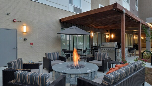 An outdoor patio with a stone fire pit, seating, and a covered area.