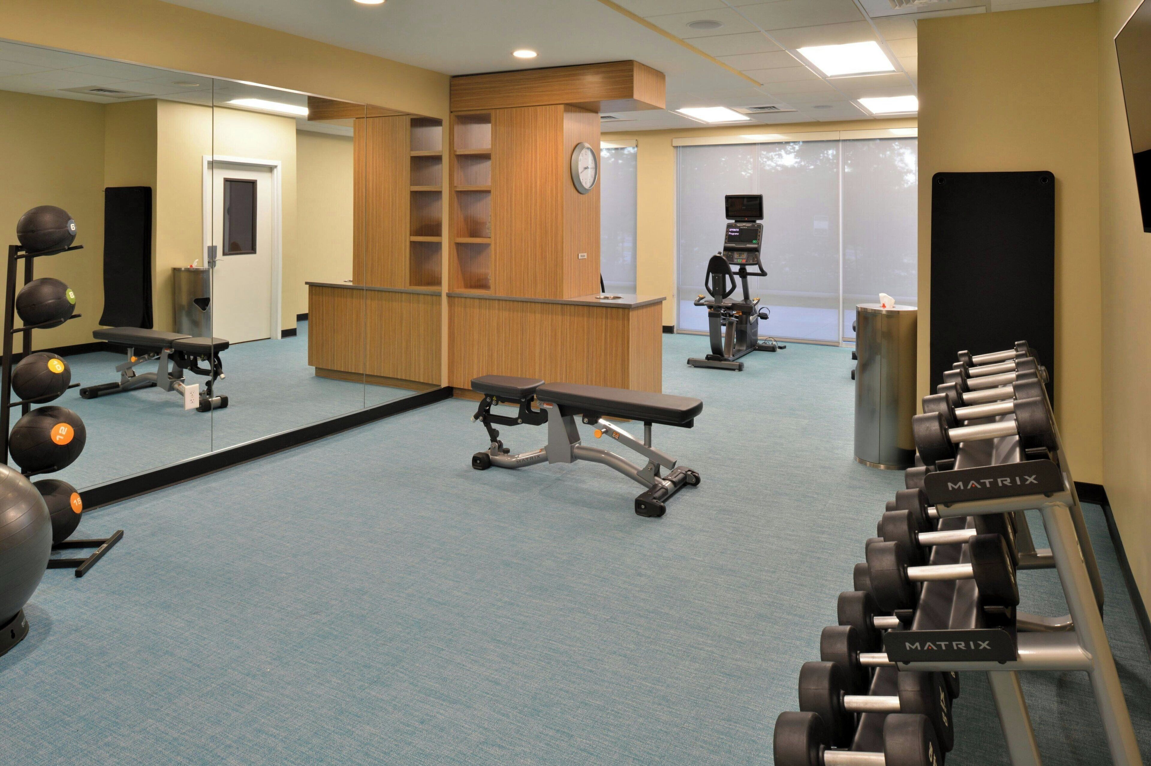 A gym with exercise equipment, a bench, and a mirrored wall.