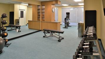 A gym with exercise equipment, a bench, and a mirrored wall.