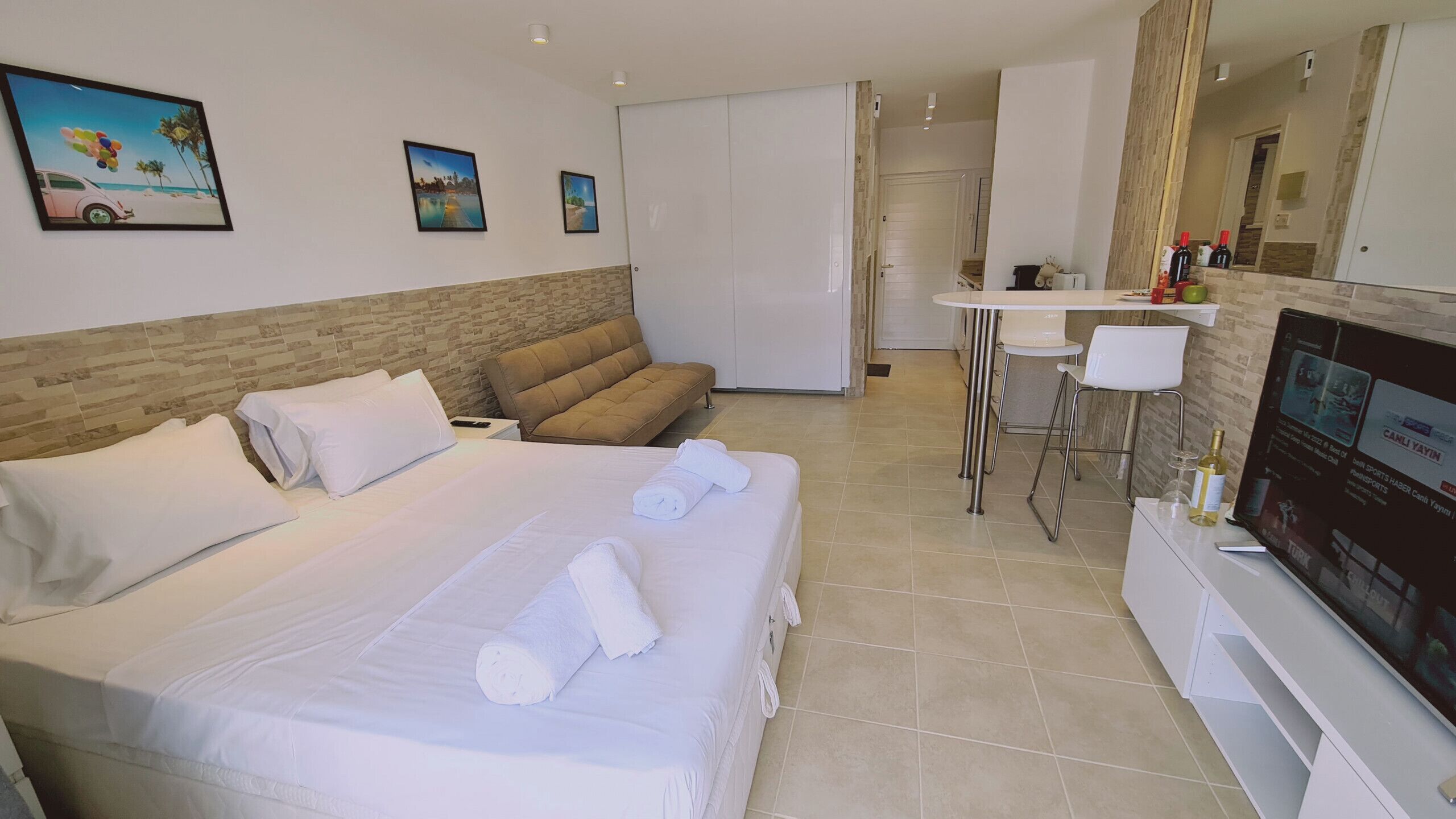 A hotel room with a bed, a sofa, a small table, and a TV.
