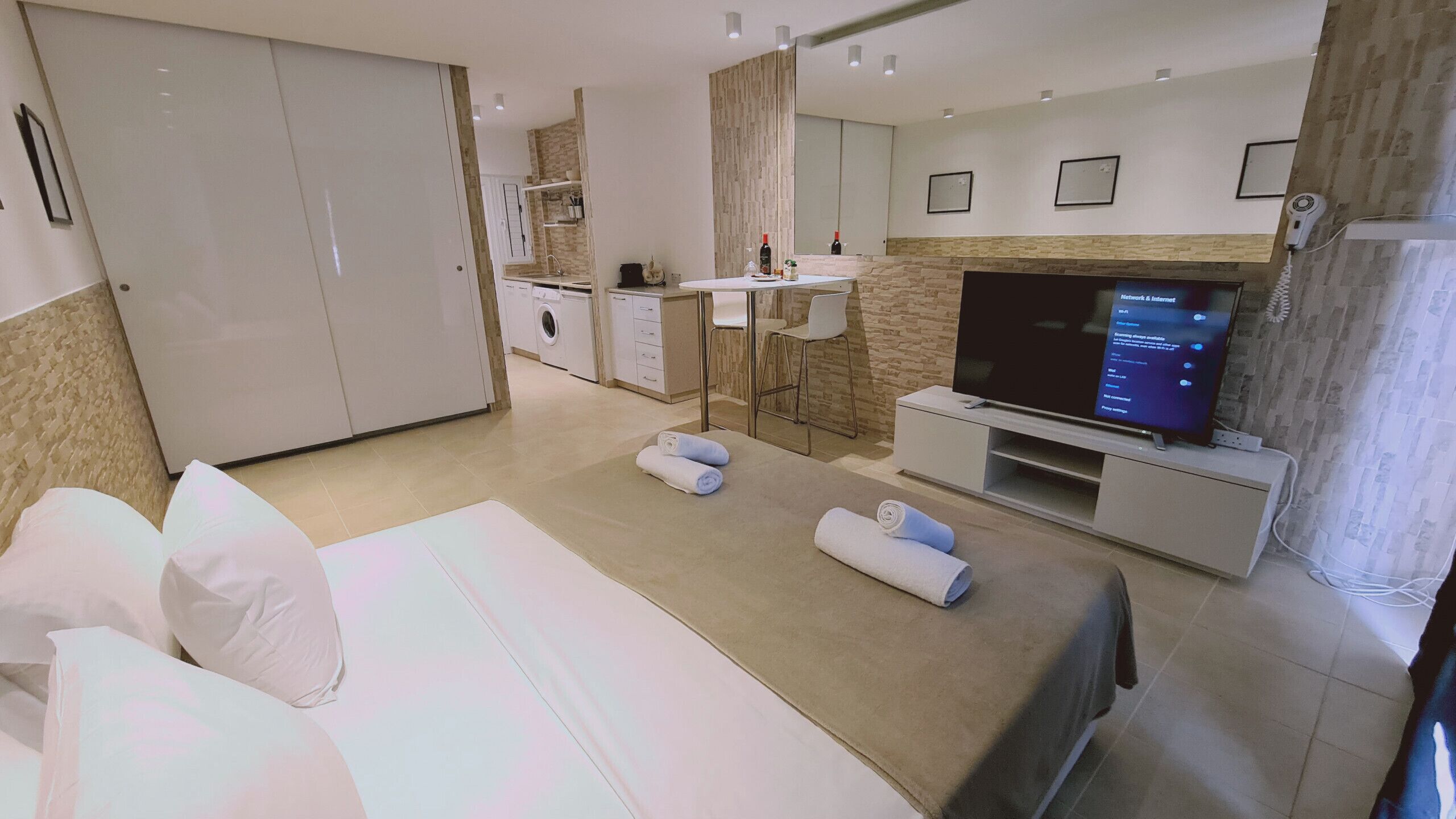 A hotel room with a bed, a TV, a desk, and a bathroom.