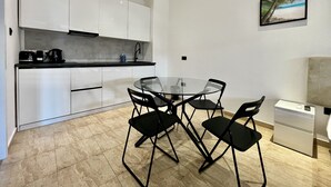 A modern kitchen with white cabinets, a black countertop, and a glass dining table with four chairs. - STAY Napa Velvet (Ayia Napa)