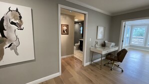Ein modernes Interieur mit Holzboden, einem Schreibtisch mit Drucker, einem gerahmten Bild an der Wand und einem großen abstrakten Gemälde.
