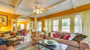 A spacious living room with a large ceiling fan, multiple seating areas including a sofa and armchairs, and a dining area visible through an archway. - Eureka Springs Vacation Rental < Half-Mi to Dtwn! (Eureka Springs)