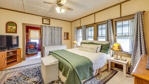 A bedroom with a bed, a television, a chair, and a window with curtains. - Eureka Springs Vacation Rental < Half-Mi to Dtwn! (Eureka Springs)