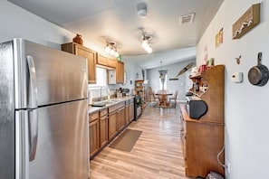 A kitchen with wooden cabinets, a stainless steel refrigerator, a dining area with a wooden table and chairs, and a wall-mounted microwave.