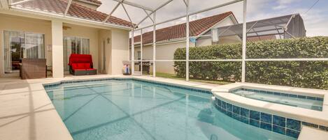An indoor swimming pool with a covered patio area, a red chair, and a barbecue grill.