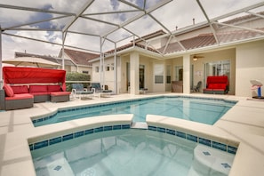 Una piscina con un patio techado, asientos exteriores y una estructura en el techo.