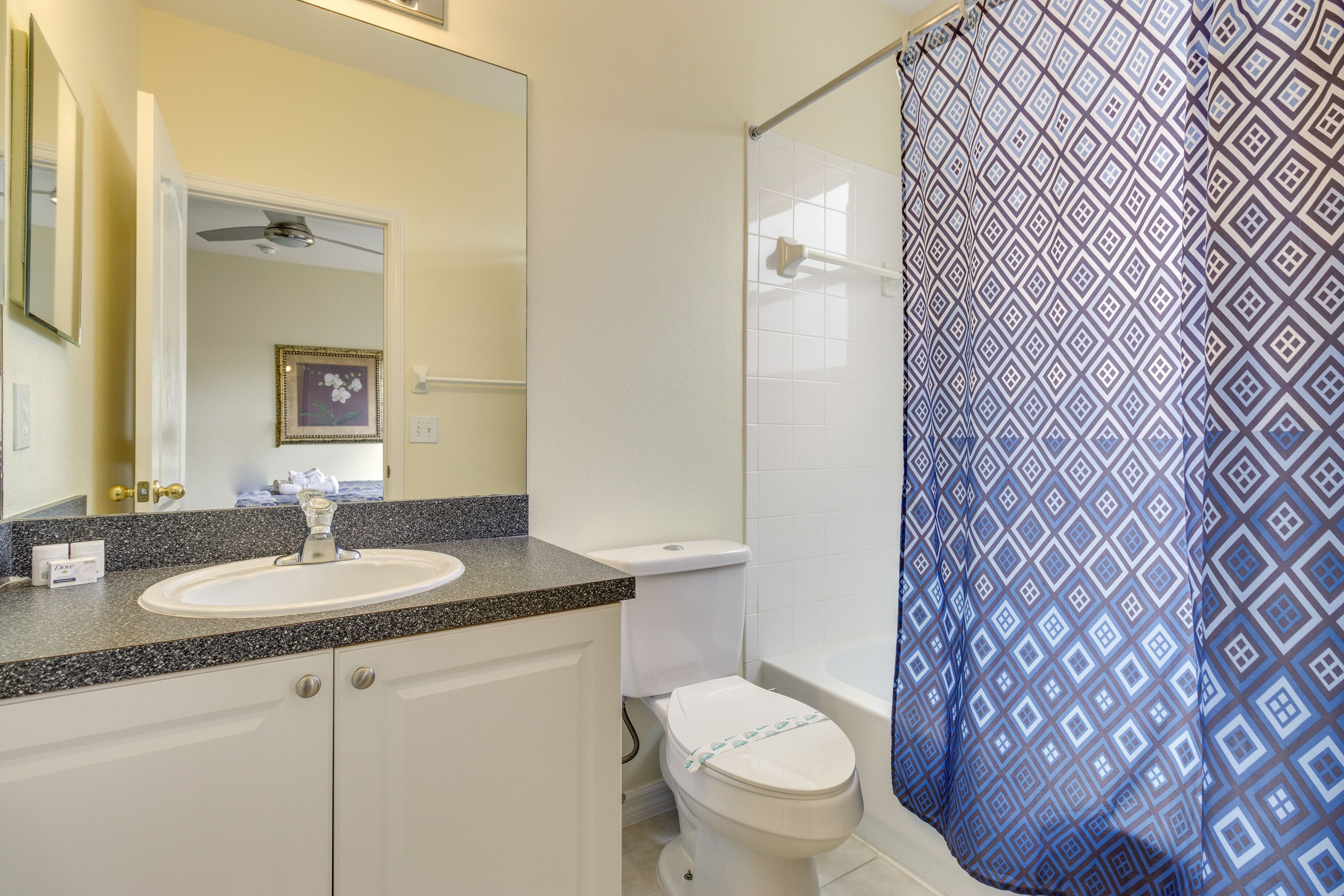 Une salle de bain avec un lavabo blanc, des toilettes et un rideau de douche à motifs géométriques.