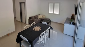 A modern kitchen with a dining area, white walls, and a window with blinds. - Escape and comfort 8-bed house with swimming pool (Val de Chaise)