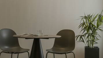 A modern dining area with a round table, two chairs, and three pendant lights.