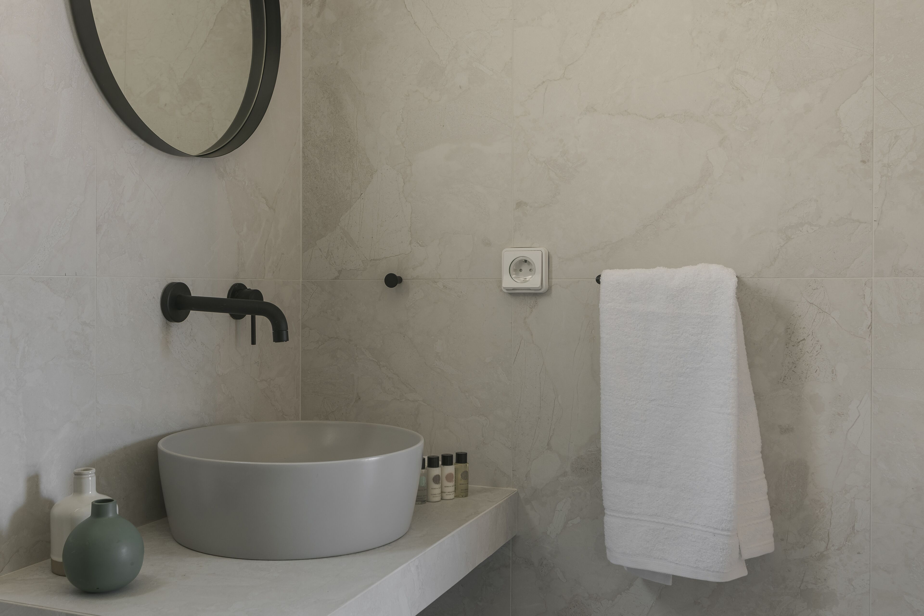 Une salle de bain avec un lavabo rond, un miroir, une serviette et des articles de toilette.