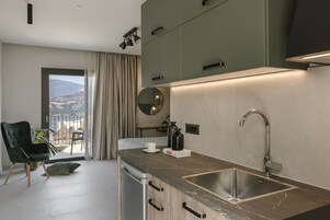 Une cuisine moderne dotée d’une grande fenêtre, d’un coin repas avec une chaise et d’une vue sur l’extérieur.