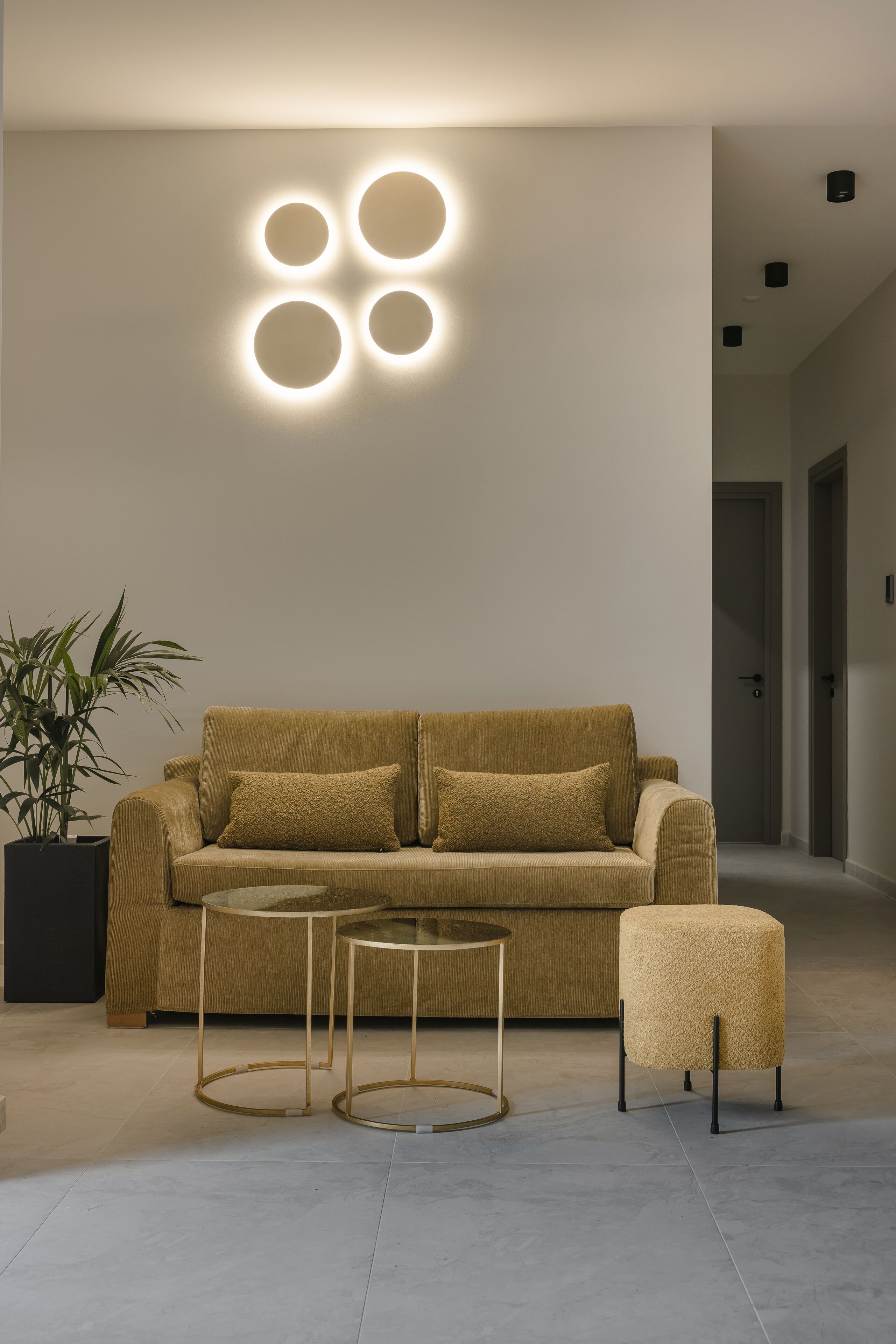 A modern living room with a sofa, two side tables, and a potted plant.