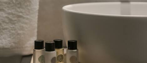 A bathroom with a white sink, a towel, and several bottles of body care products.