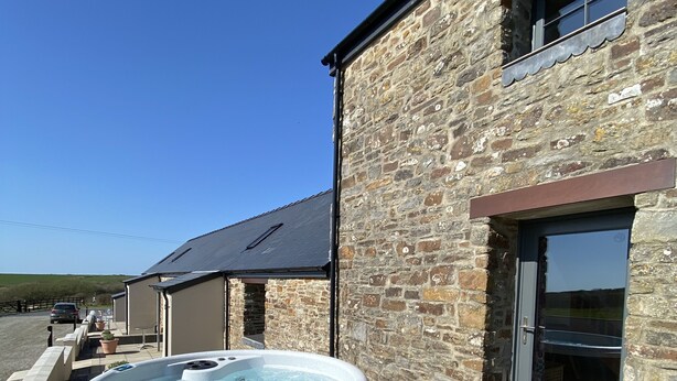 A stone building with a hot tub and outdoor seating.