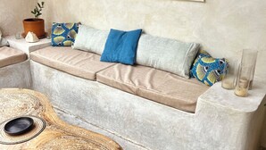 Un rincón acogedor con un banco acolchado, una mesa redonda de madera y una planta en maceta.