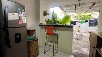 Une cuisine compacte équipée d’un réfrigérateur, d’un évier et d’un tabouret de bar.