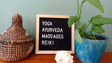A wooden table with a blackboard displaying "YOGA, AYURVEDA, MASSAGES, REIKI" and a potted plant.