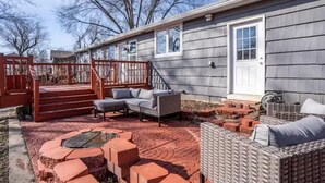 A covered patio area with outdoor furniture, a fire pit, and a brick wall.