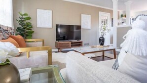 A modern living room with a sofa, a coffee table, a TV, and a plant.