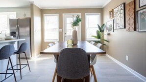 A modern kitchen with a dining area, featuring a large table, chairs, and a refrigerator.