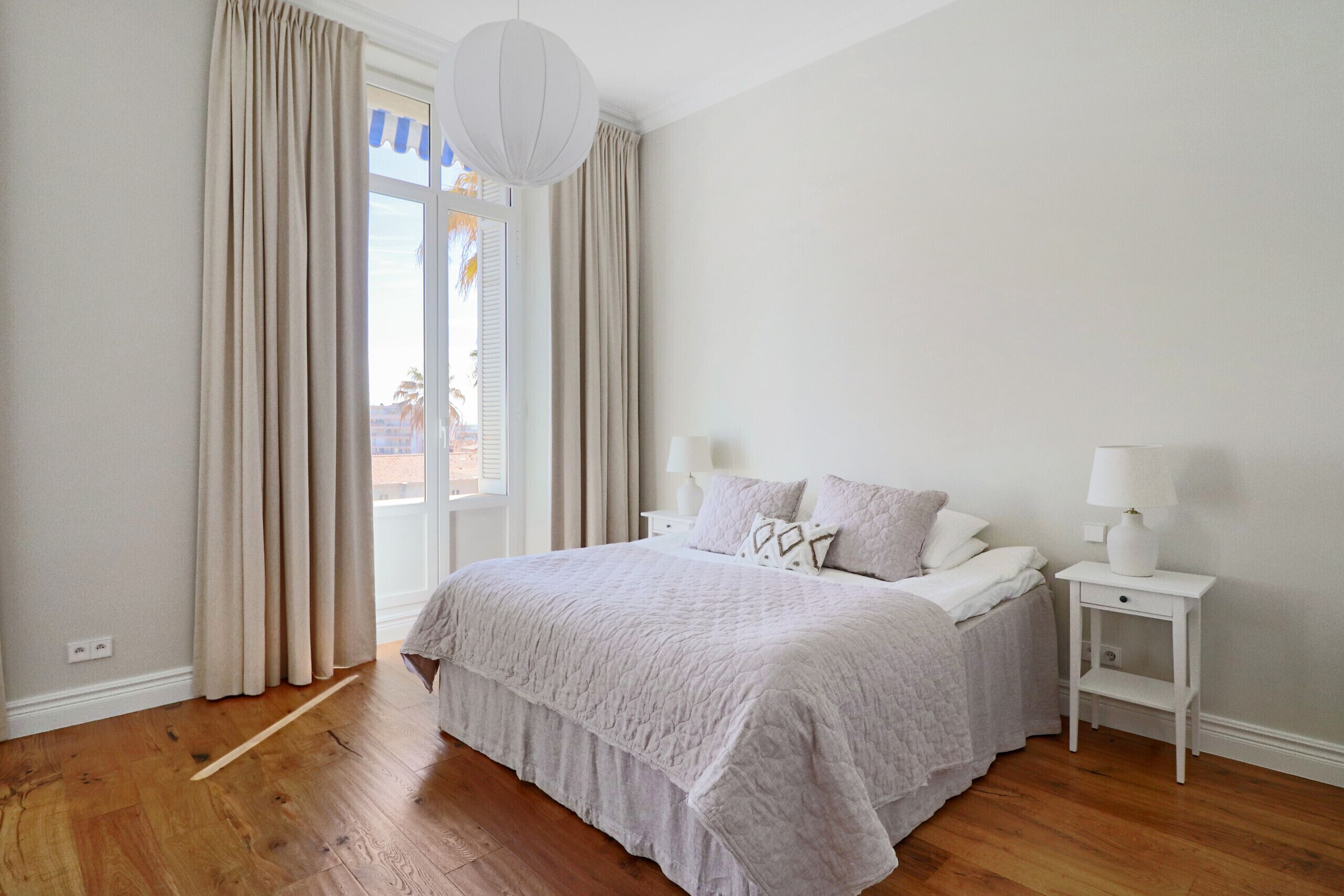 Une chambre à coucher avec un lit, des tables de chevet et une vue par la fenêtre.