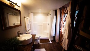Ein Badezimmer mit Waschbecken, Toilette und Dusche. Ein Handtuchhalter und ein Spiegel befinden sich über dem Waschbecken.