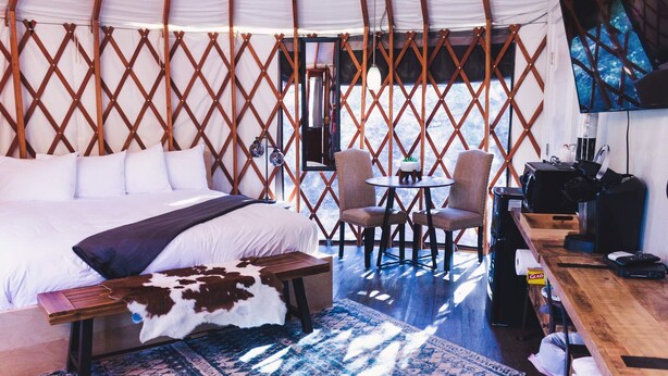Ein gemütliches Zimmer mit einem Bett, einem kleinen Tisch, zwei Stühlen und einem Fernseher.