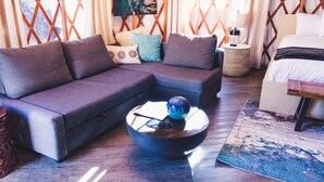 Ein modernes Wohnzimmer mit einem Ecksofa, einem runden Couchtisch mit dekorativer Schale und einem gemusterten Teppich.