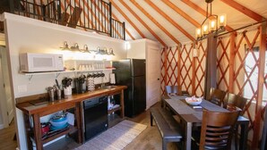 Una cocina compacta equipada con microondas, refrigerador y una mesa de madera con sillas.
