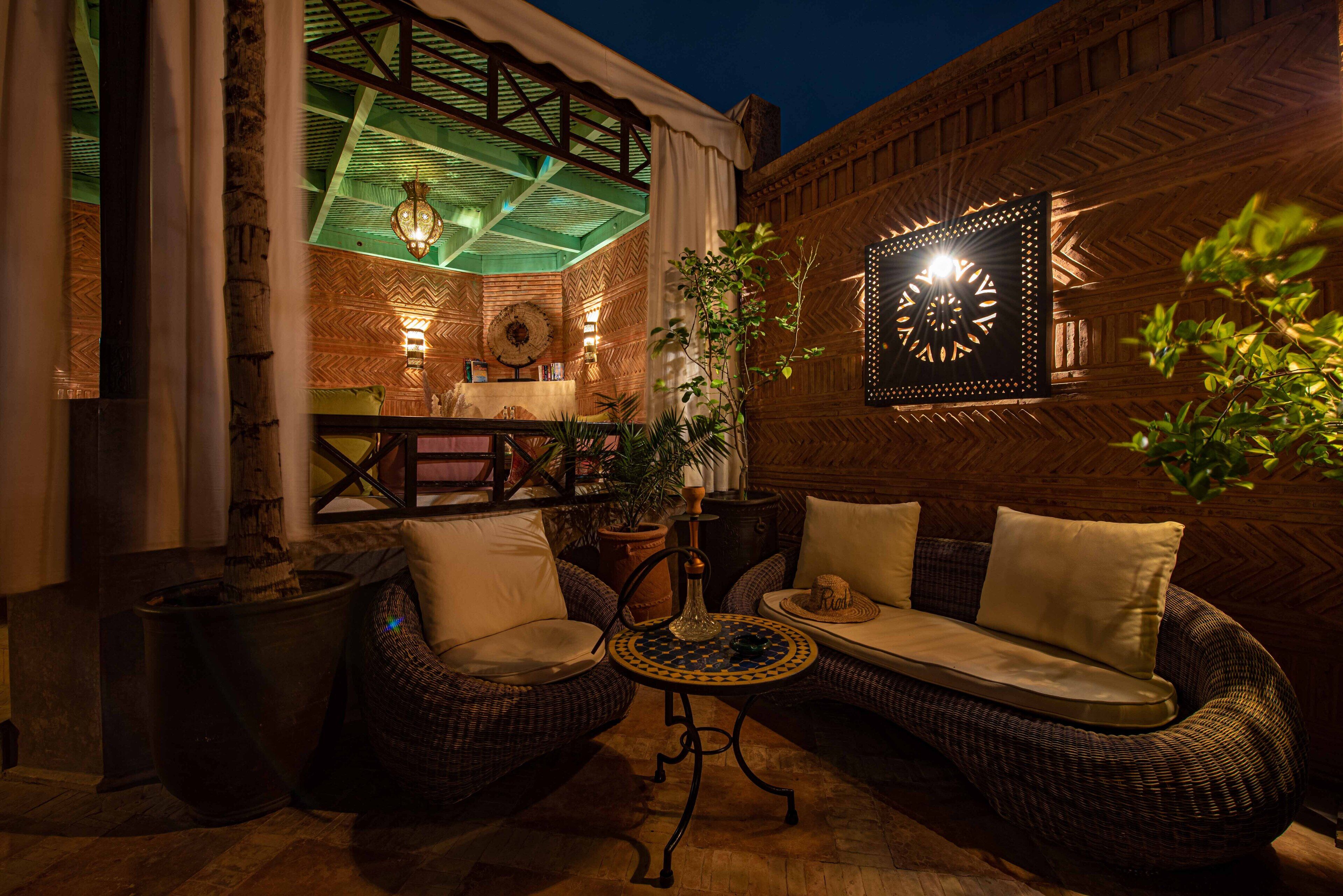 An outdoor seating area with wicker furniture, a table, and a decorative wall piece.