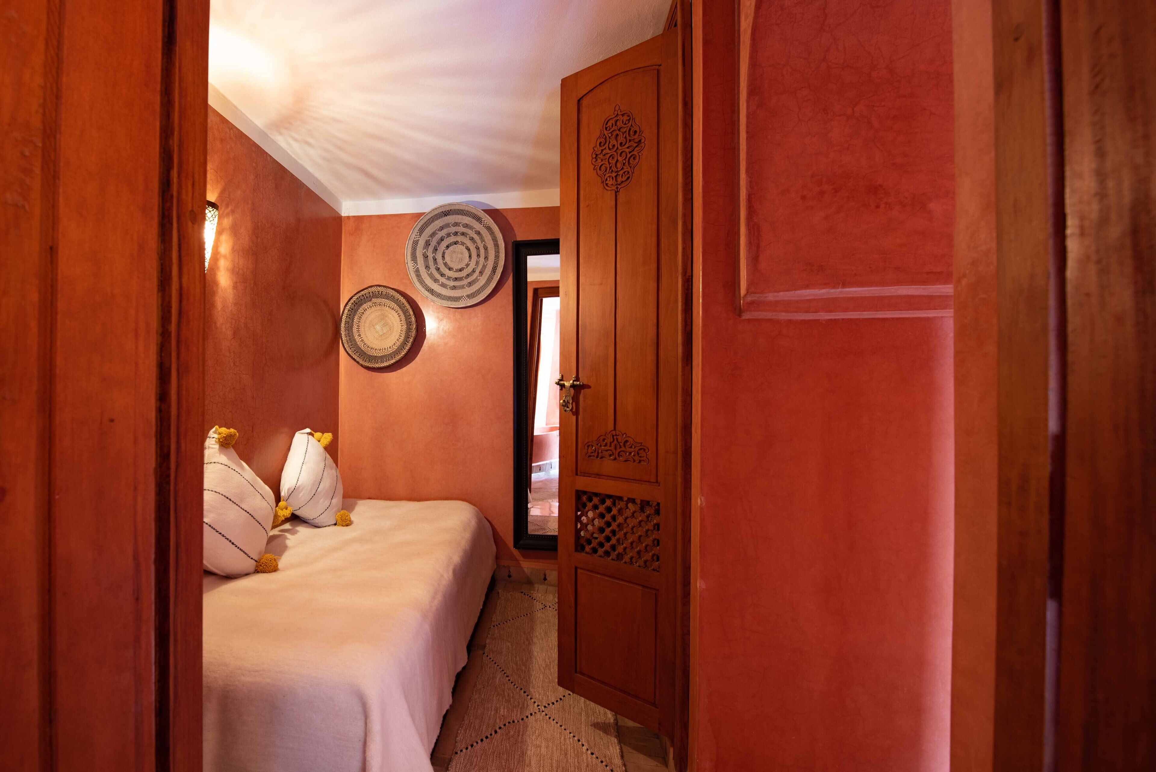 A bedroom with a bed, pillows, a wooden door, and wall decor.