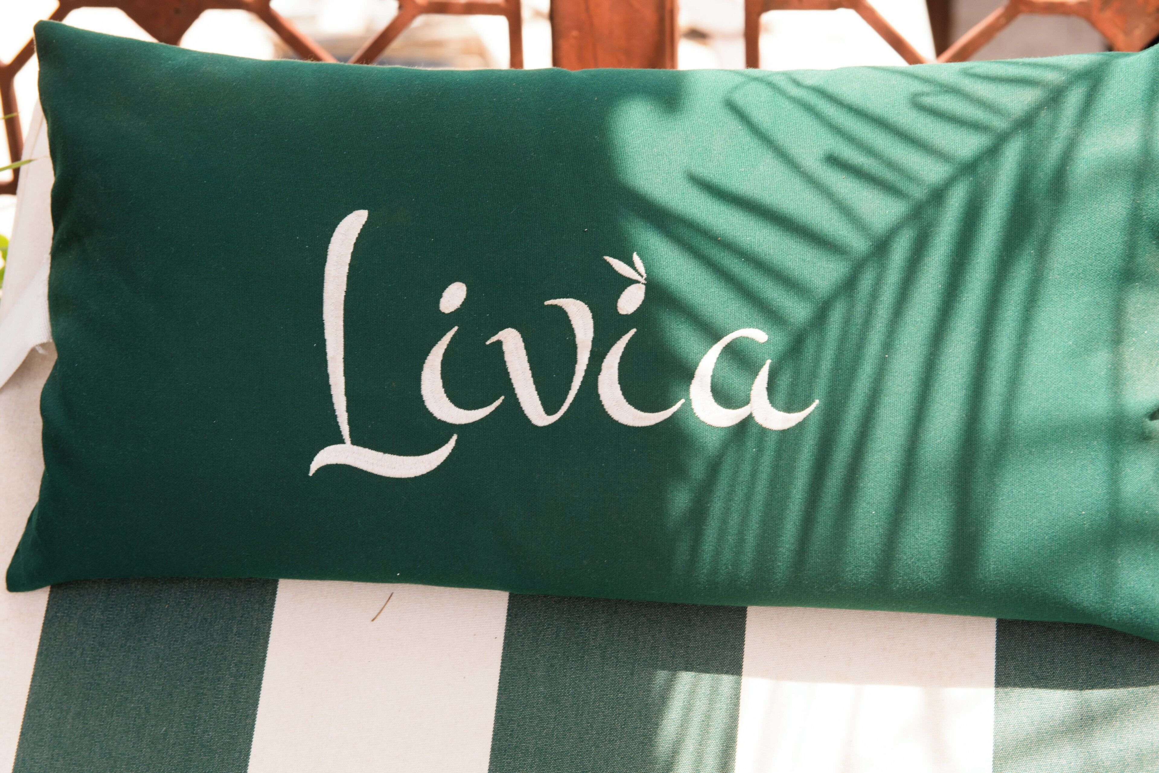 A green pillow with the name 'Livia' embroidered on it.