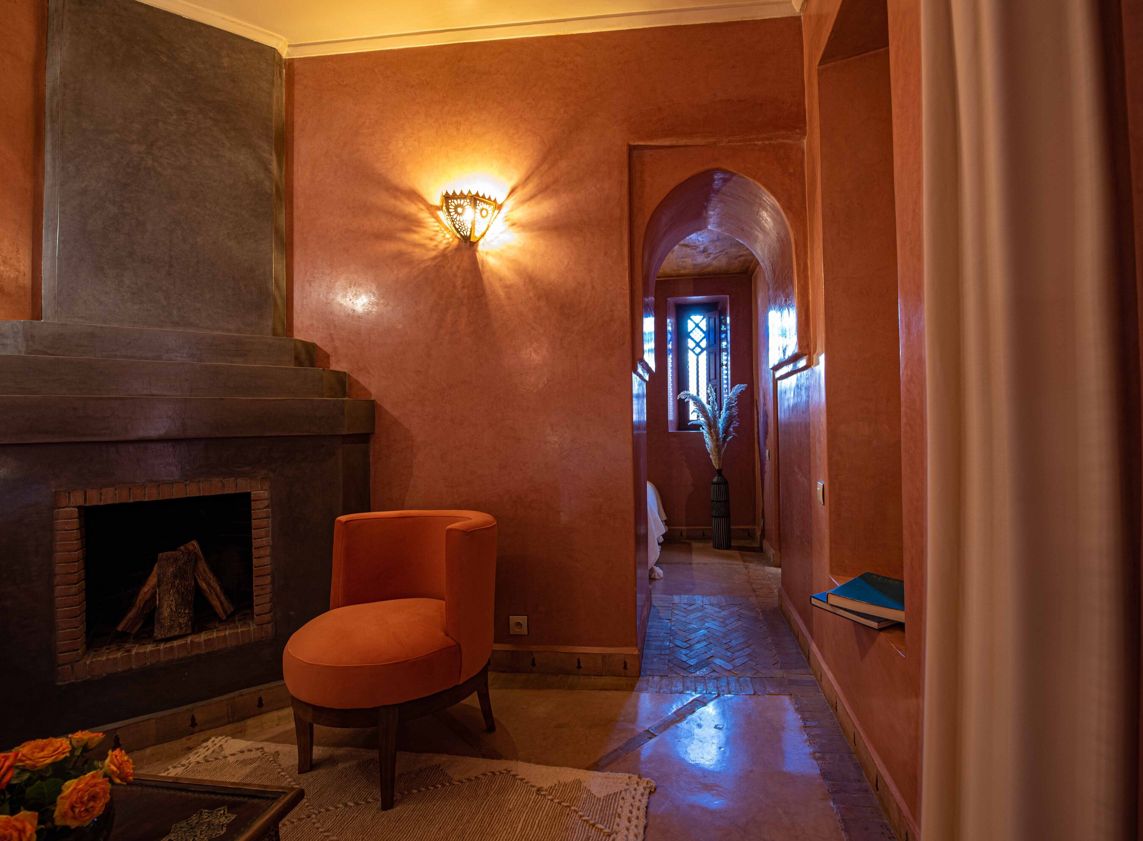 A hallway with a fireplace, a chair, and a wall-mounted light fixture.