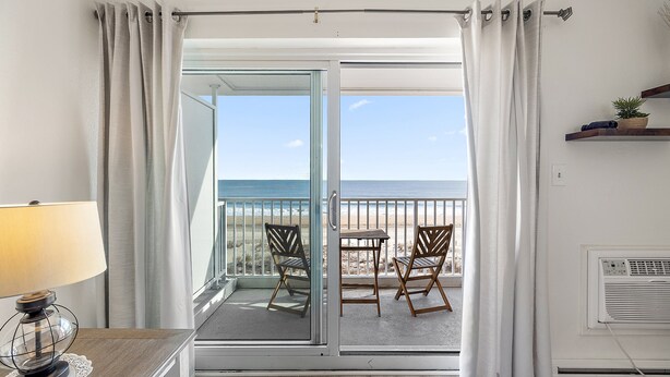Ein Balkon mit Meerblick, einem Tisch und Stühlen sowie einer Lampe.