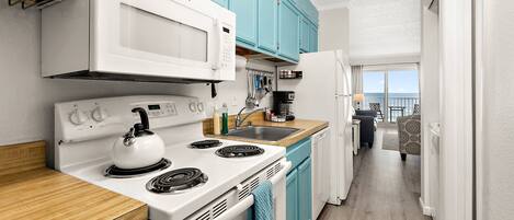 A compact kitchen with teal cabinets, a white stove, and a wooden countertop.
