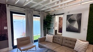 Una sala de estar moderna con sofá, sillón, mesa de centro redonda y dos otomanas.