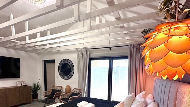 Un dormitorio moderno con una cama grande, un ventilador de techo, un reloj y vistas al exterior.