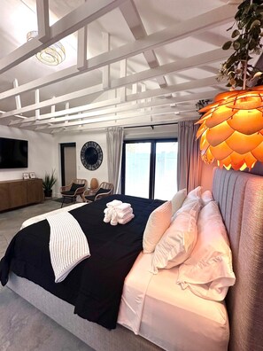 A modern bedroom with a large bed, a ceiling fan, a clock, and a view of the outdoors. - Zen.Modern.Hip “Studio 501” Beach|Scuba|Downtown (West Palm Beach)