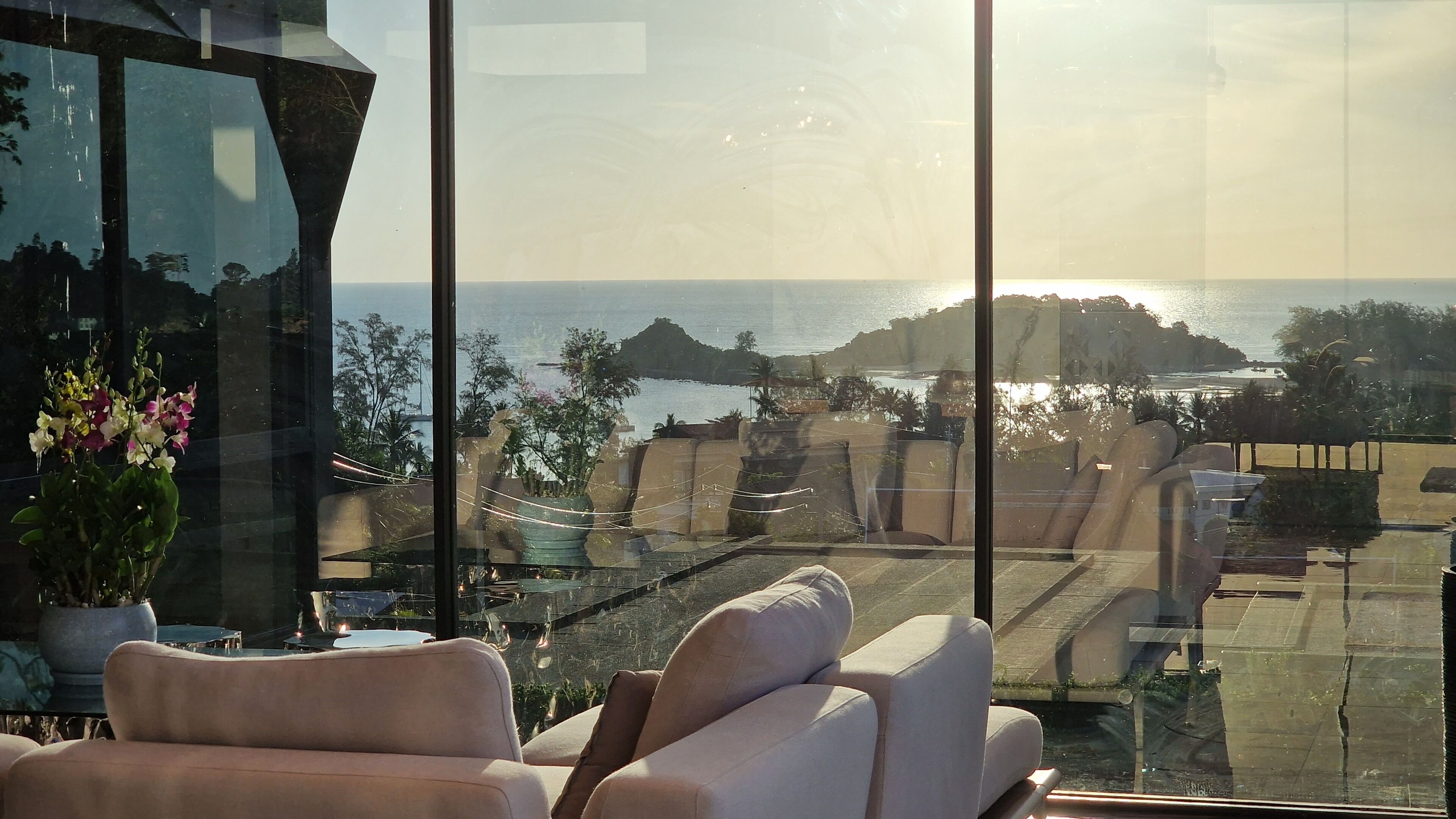 A room with a large window overlooking a coastal view, including a body of water and distant land.