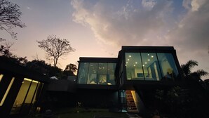 A modern house with large glass windows, a staircase leading to the entrance, and a well-maintained garden. - Luxury private 3 Ultra-King BR, with staff, villa sea view 10min walk to beach (Surat Thani)