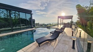 A modern outdoor pool area with lounge chairs and a pergola. - Luxury private 3 Ultra-King BR, with staff, villa sea view 10min walk to beach (Surat Thani)
