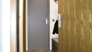 Um corredor com uma porta de madeira, uma porta cinza no final e um casaco pendurado na porta.